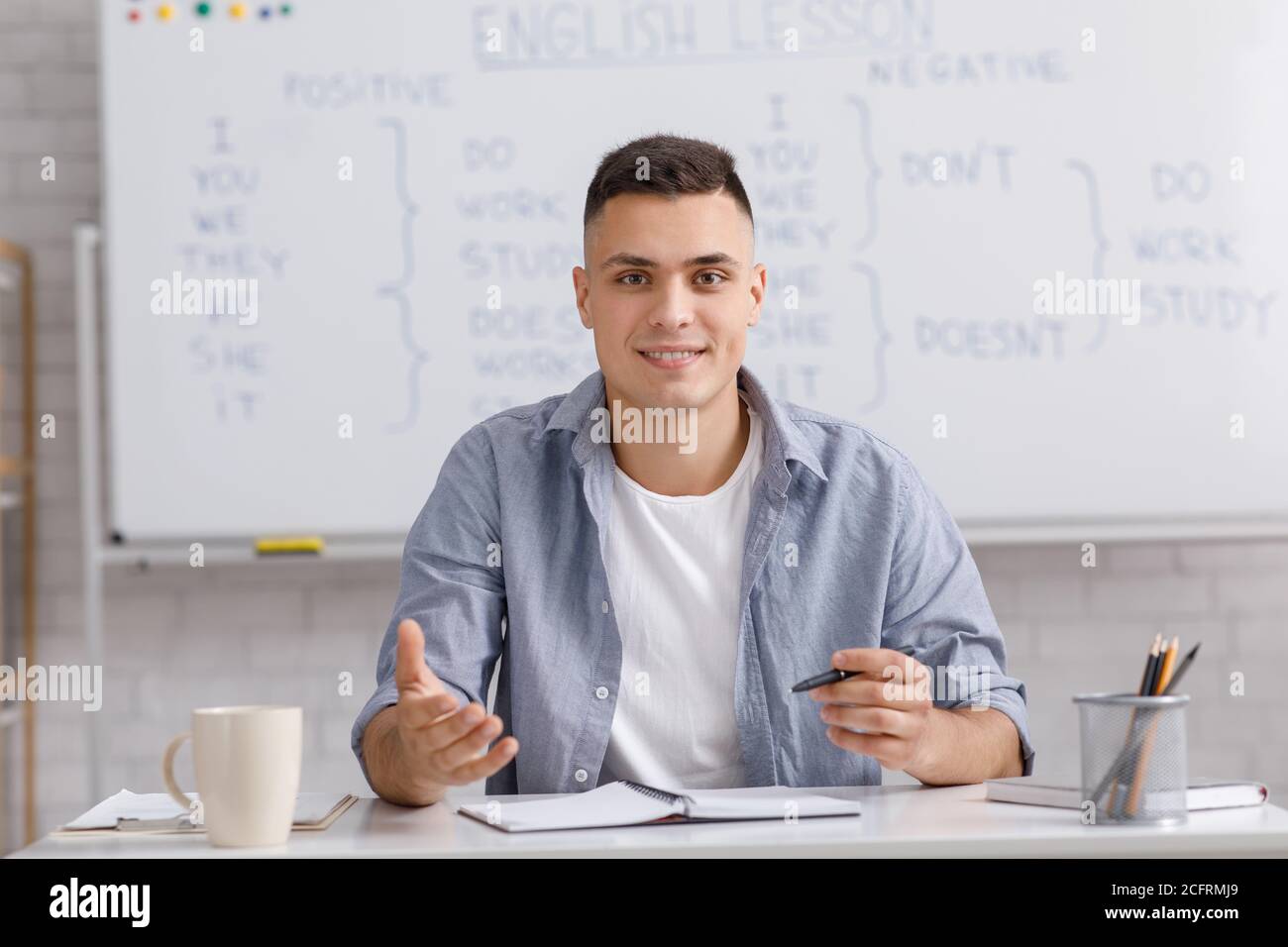 Insegnante online che parla con webcam, seduto al tavolo in ufficio e spiegare le regole grammatica inglese Foto Stock