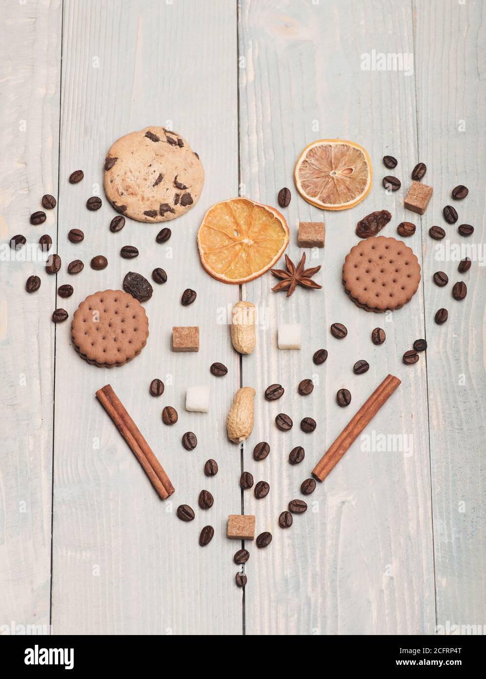 Modello composto da chicchi di caffè, biscotti, arancia secca, anice e  cannella. Cuore fatto di cibo e spezie su sfondo di legno chiaro vintage.  Il simbolo dell'amore è sinonimo di dolce sensazione.