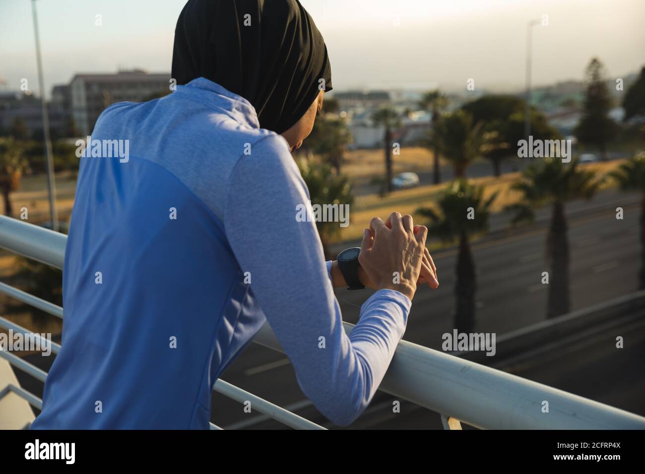 Donna in hijab che usa lo smartwatch su un ponte Foto Stock