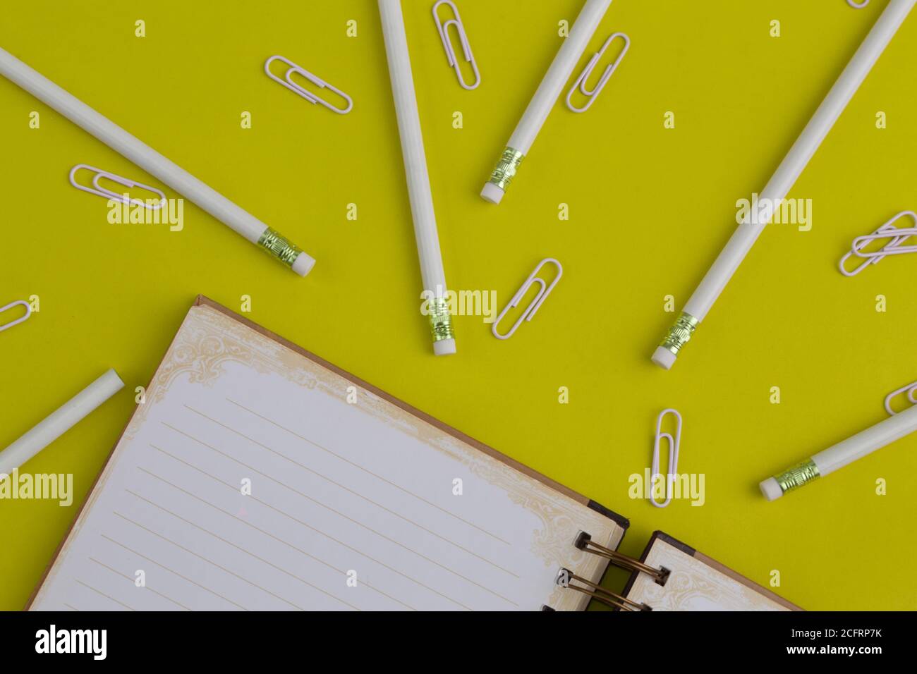 matite, clip e un notebook, oggetti da ufficio su uno sfondo colorato e divertente Foto Stock