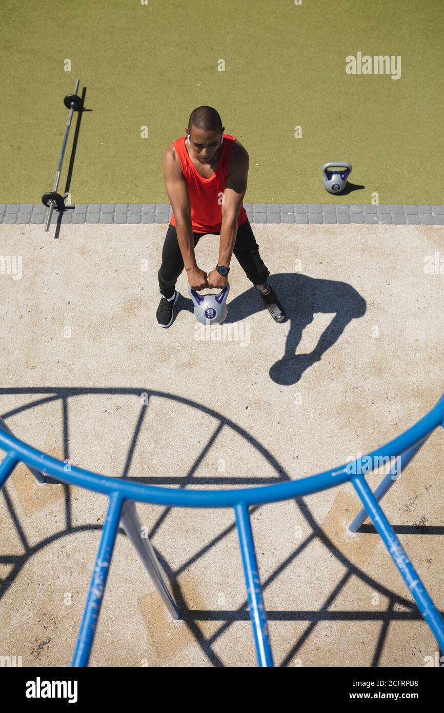 Uomo con gamba protesica che si sta allenando utilizzando il bicchiere del bollitore il parco Foto Stock