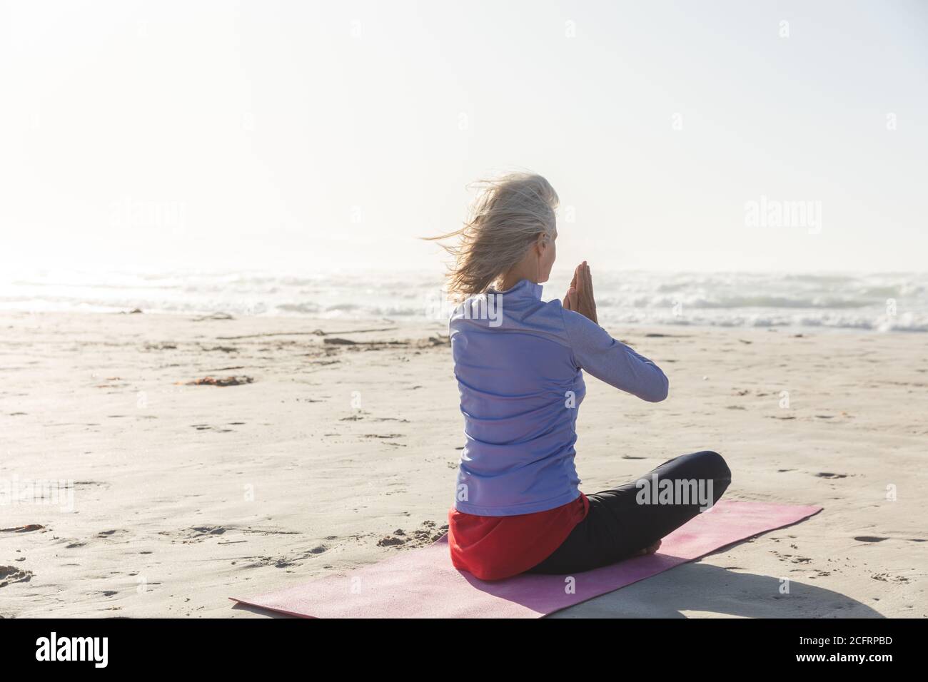 Vista posteriore della donna che pratica yoga sulla spiaggia Foto Stock