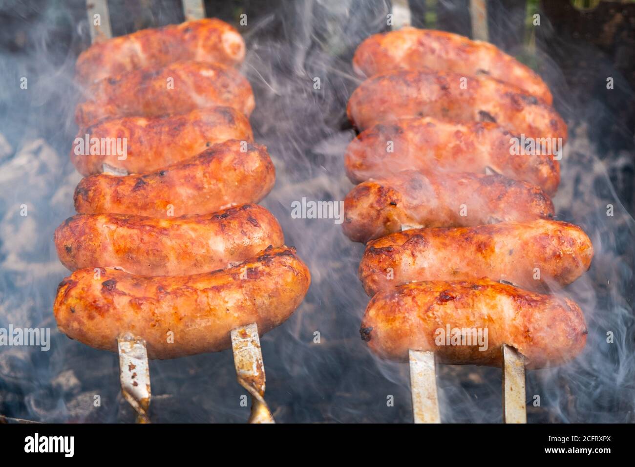 salsicce di maiale spiedate con crosta fritta, grigliate, cibi cotti in primo piano all'aperto. Foto Stock