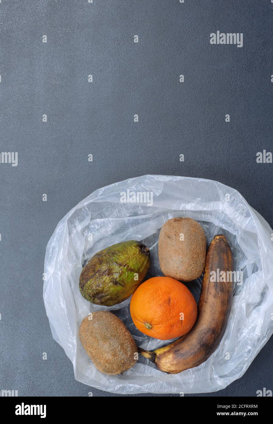 Cibo viziato. Kiwi, banana, arancio e avocado nel sacchetto di plastica. Rifiuti alimentari. Spazzatura discarica cibo marcio. Spazio di copia. Concetto di frutta marcio. Foto Stock