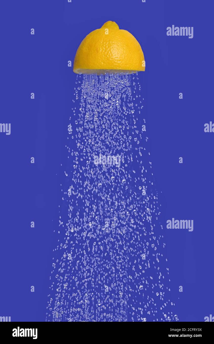 Concettuale acqua che scorre doccia da Squeeze metà di UN limone Foto Stock