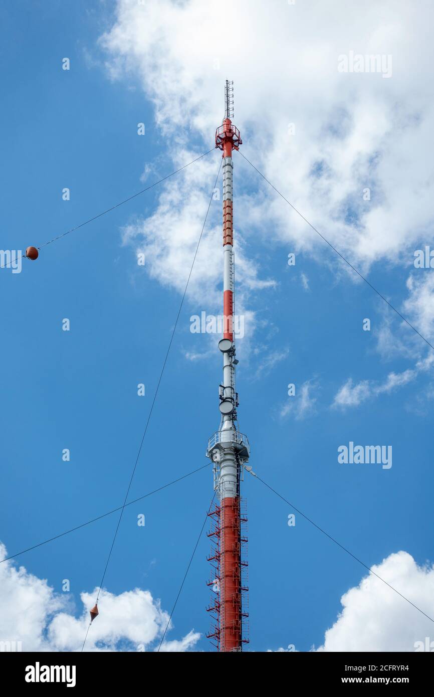 Montante di trasmissione contro il cielo blu con nuvole bianche Foto Stock