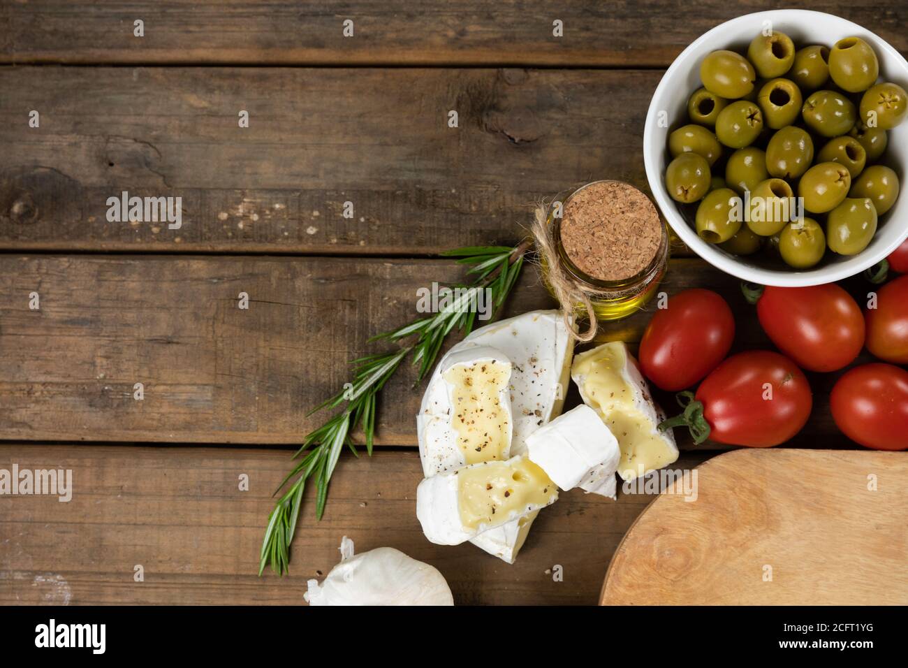 Vista su un tagliere di legno con pane, formaggio, salsiccia, frutta e vino su una superficie di legno Foto Stock