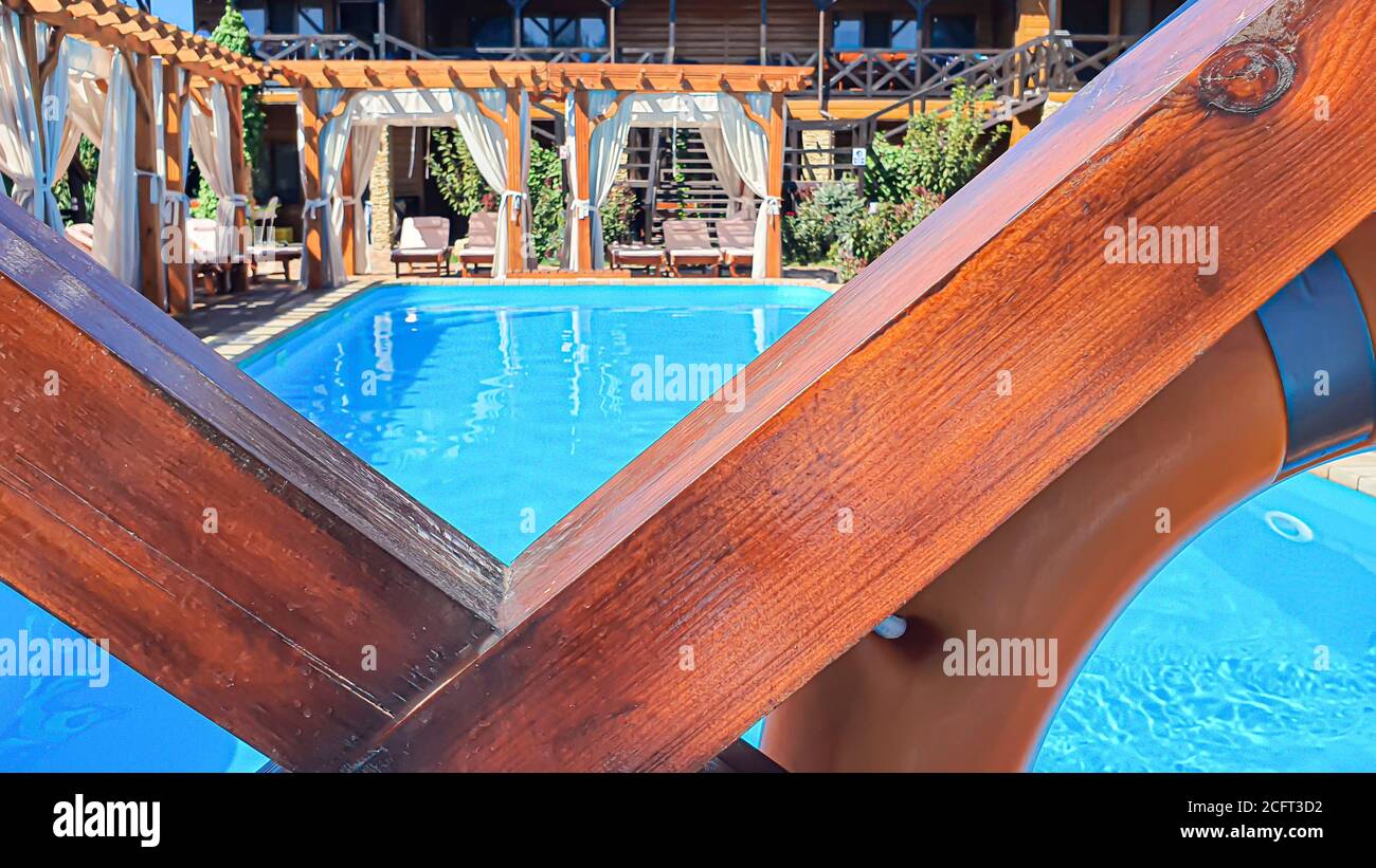 Un cortile con piscina, lettini e un parco giochi in legno ecologico. Vacanze estive per tutta la famiglia. Benessere. Foto Stock