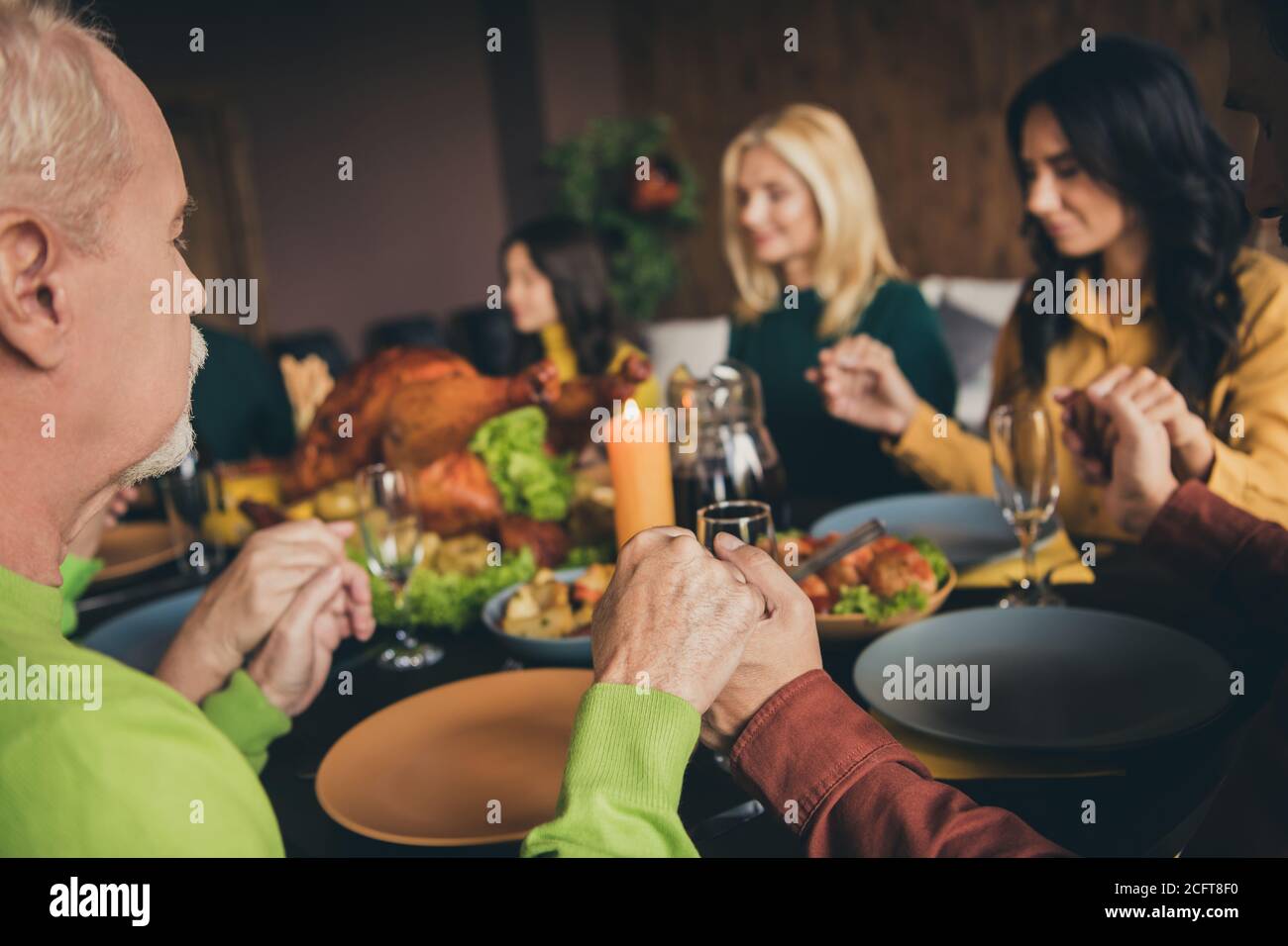 Ritratto di bella bella tranquilla calma famiglia religiosa seduta intorno tavolo che tiene le mani che pregano mangiando piatto da pranzo festoso fatto in casa moderno Foto Stock