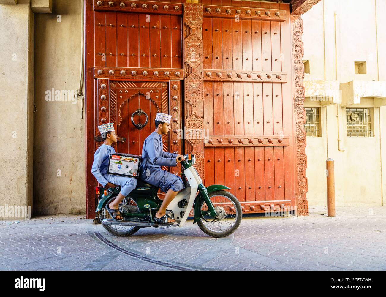 Nizwa, Oman, 2 dicembre 2016: Due ragazzi su una moto stanno lasciando Nizwa Friday Market con un acquisto Foto Stock