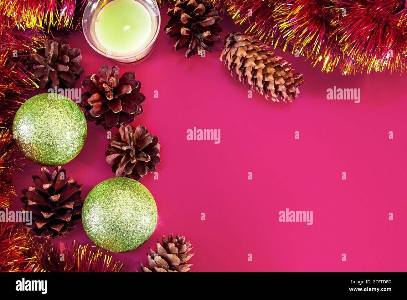 Decorazioni natalizie - coni, palle natalizie e rami su sfondo rosa. Aroma candela per una piacevole vacanza. Inserire il testo. Foto Stock