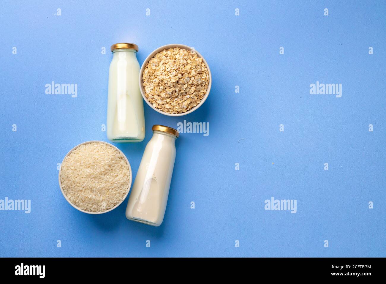 Latte di avena e riso vegano in bottiglie di vetro blu sfondo Foto Stock