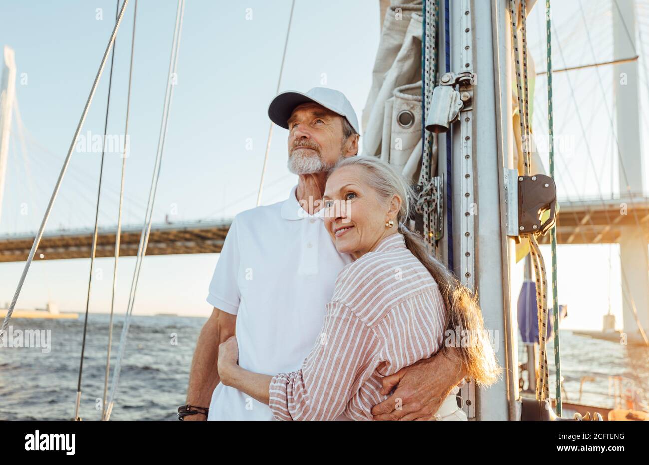 Affettuosa coppia anziana che si unisce e guarda in lontananza mentre si è in piedi su uno yacht Foto Stock