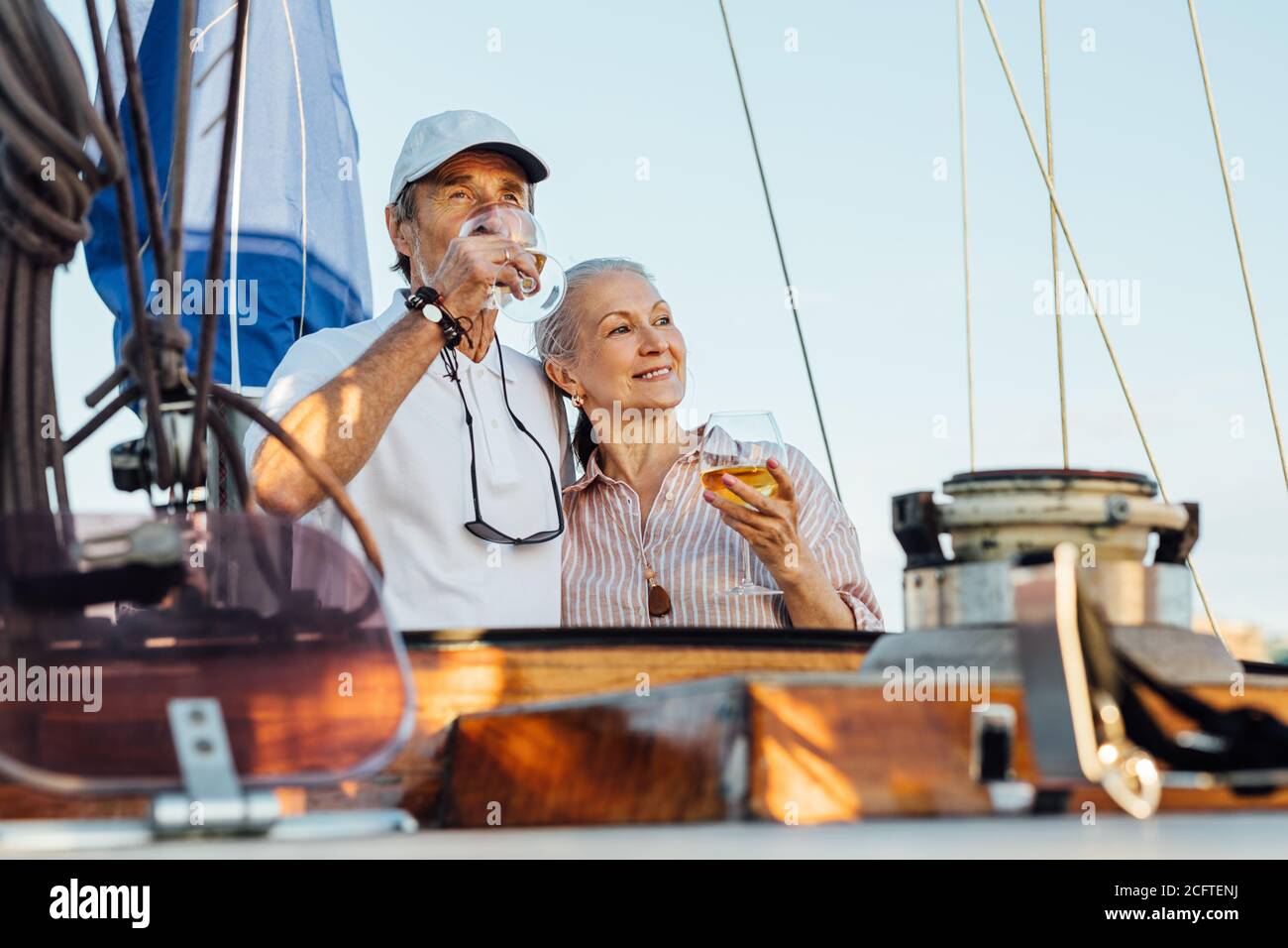 Ritratto di una coppia senior in piedi su una barca a vela privata e bere vino. Donna e uomo con bocali di vino su yacht godendo di viaggio. Foto Stock