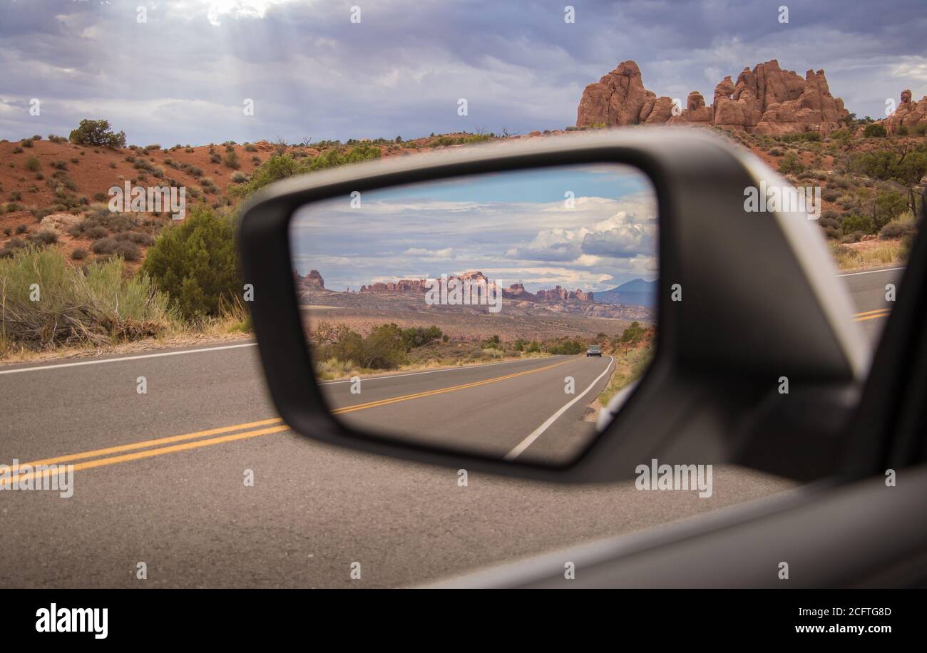 Una vista delle formazioni rocciose nello specchietto retrovisore Di una macchina che guida nel Parco Nazionale di Arches Foto Stock