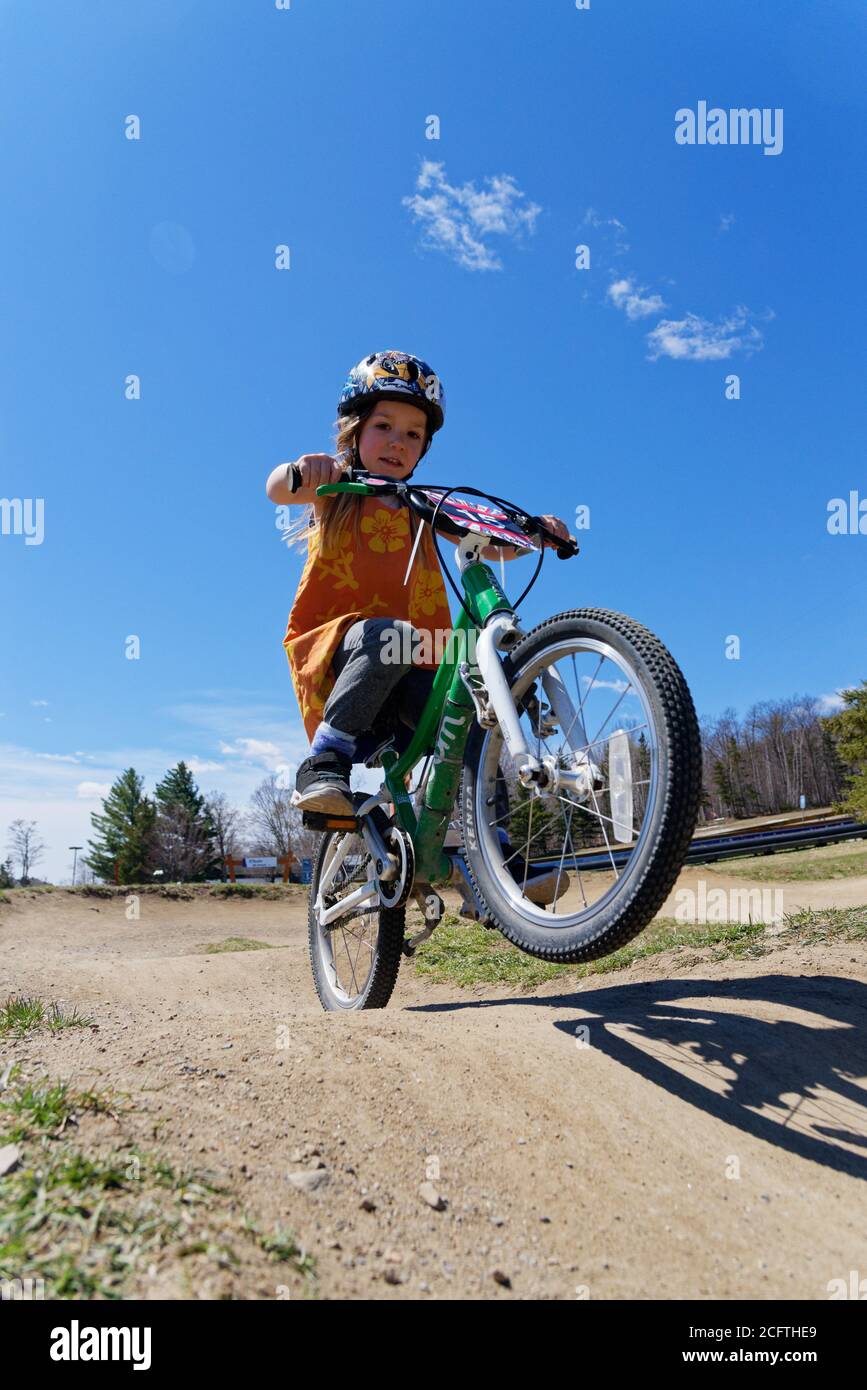 Una bambina (5 anni) schioccando una ruota sulla sua bici Foto Stock