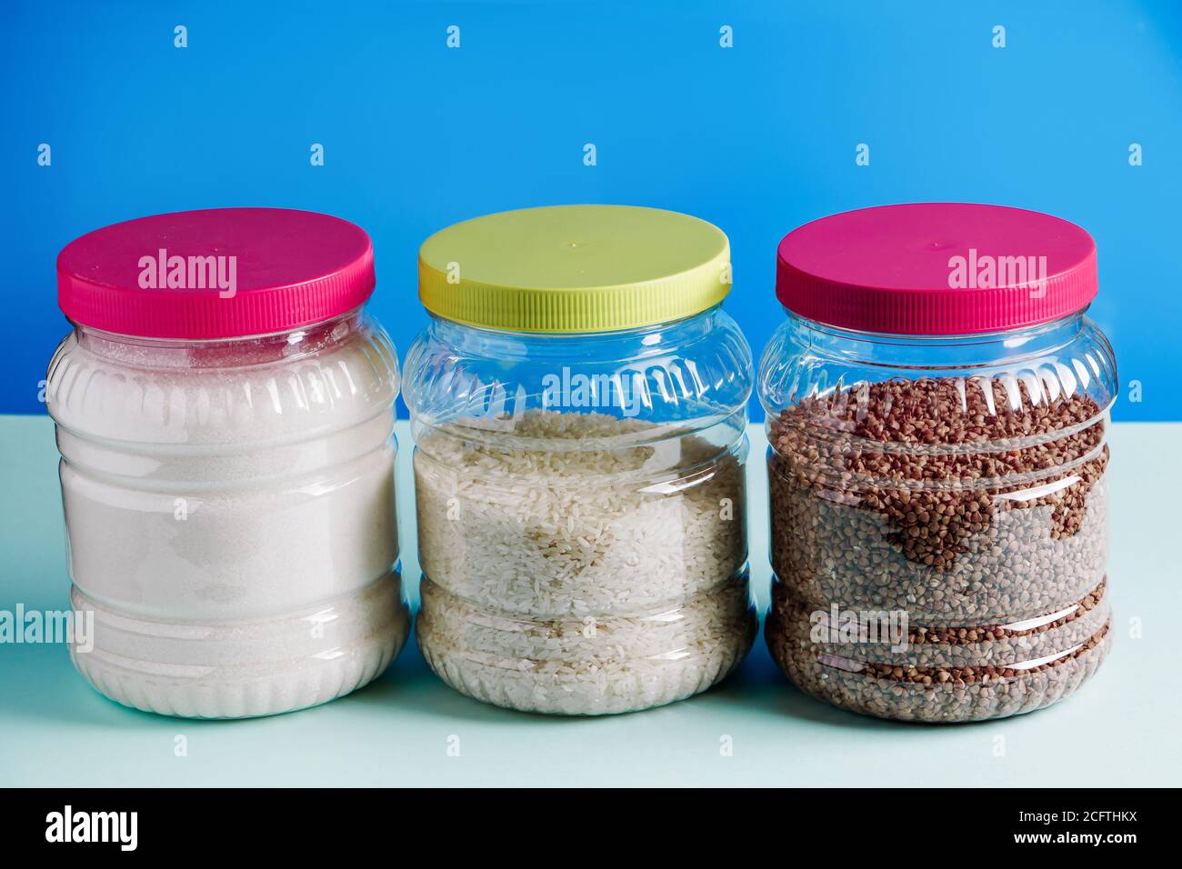 Vasi con cereali e zucchero su sfondo blu. Articoli essenziali per lo shopping in quarantena. Foto Stock