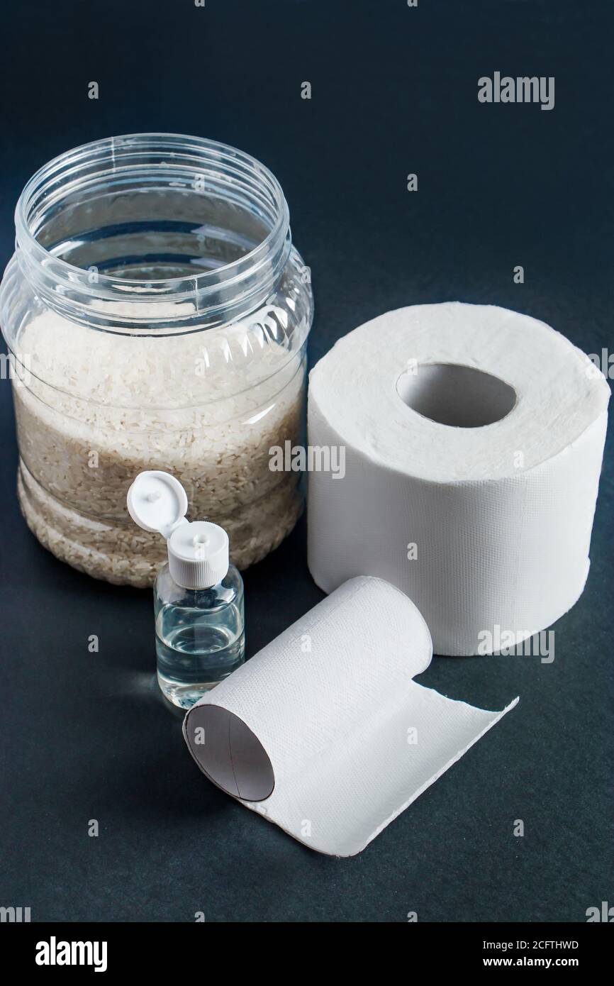 Indispensabili per la quarantena domestica - carta igienica, cibo, antisettico su sfondo nero. La pandemia del coronavirus nel mondo. Foto Stock