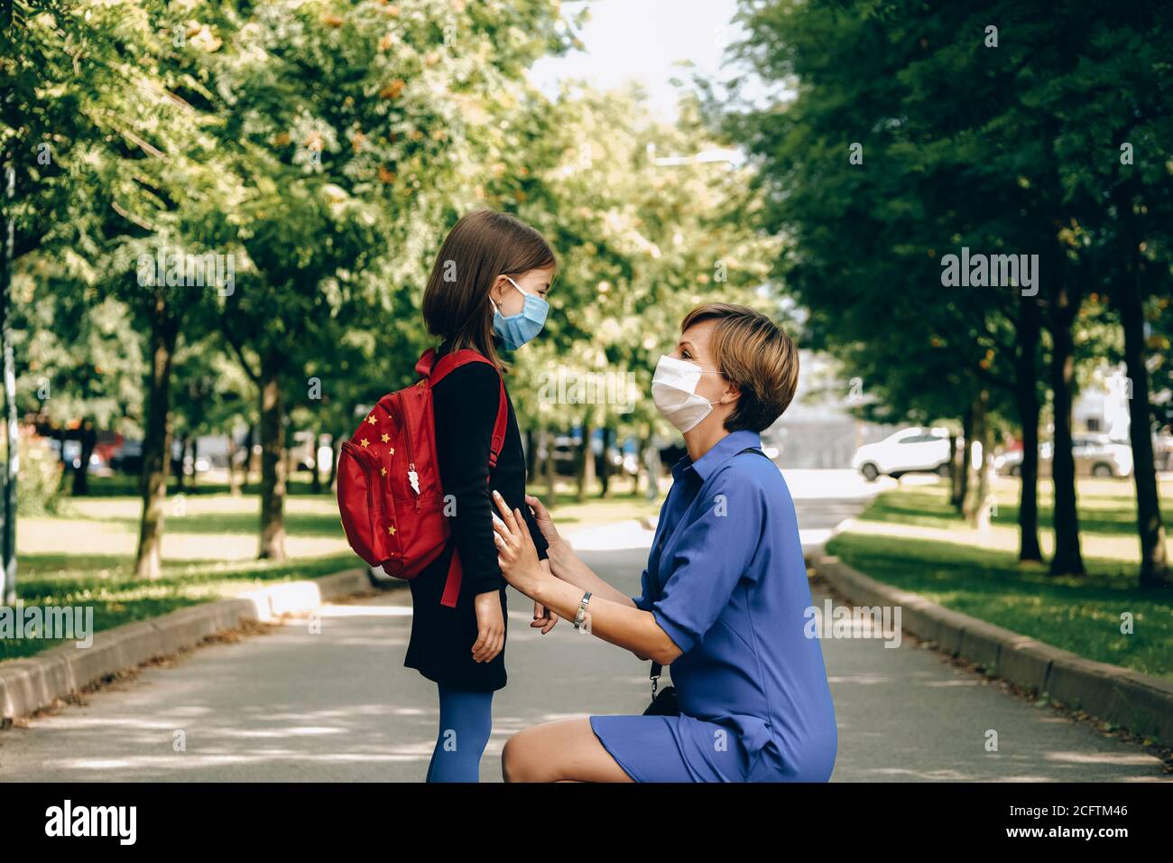 la madre che indossa una maschera protettiva sta vedendo la figlia. Concetto di ritorno a scuola. Foto Stock