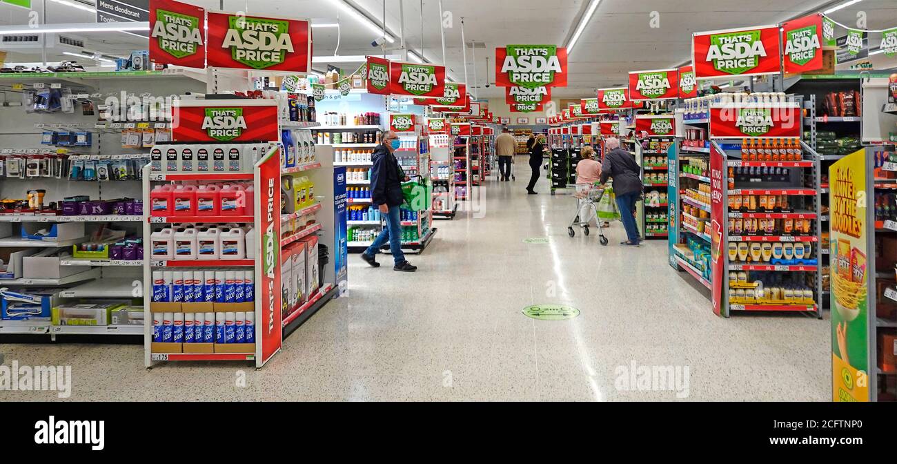 Il personale di acquisti del Coronavirus in Covid 19 maschere facciali Asda supermercato negozio alimentare corona virus sociale uomo di distanza con cesto di indossare Maschera Inghilterra UK Foto Stock