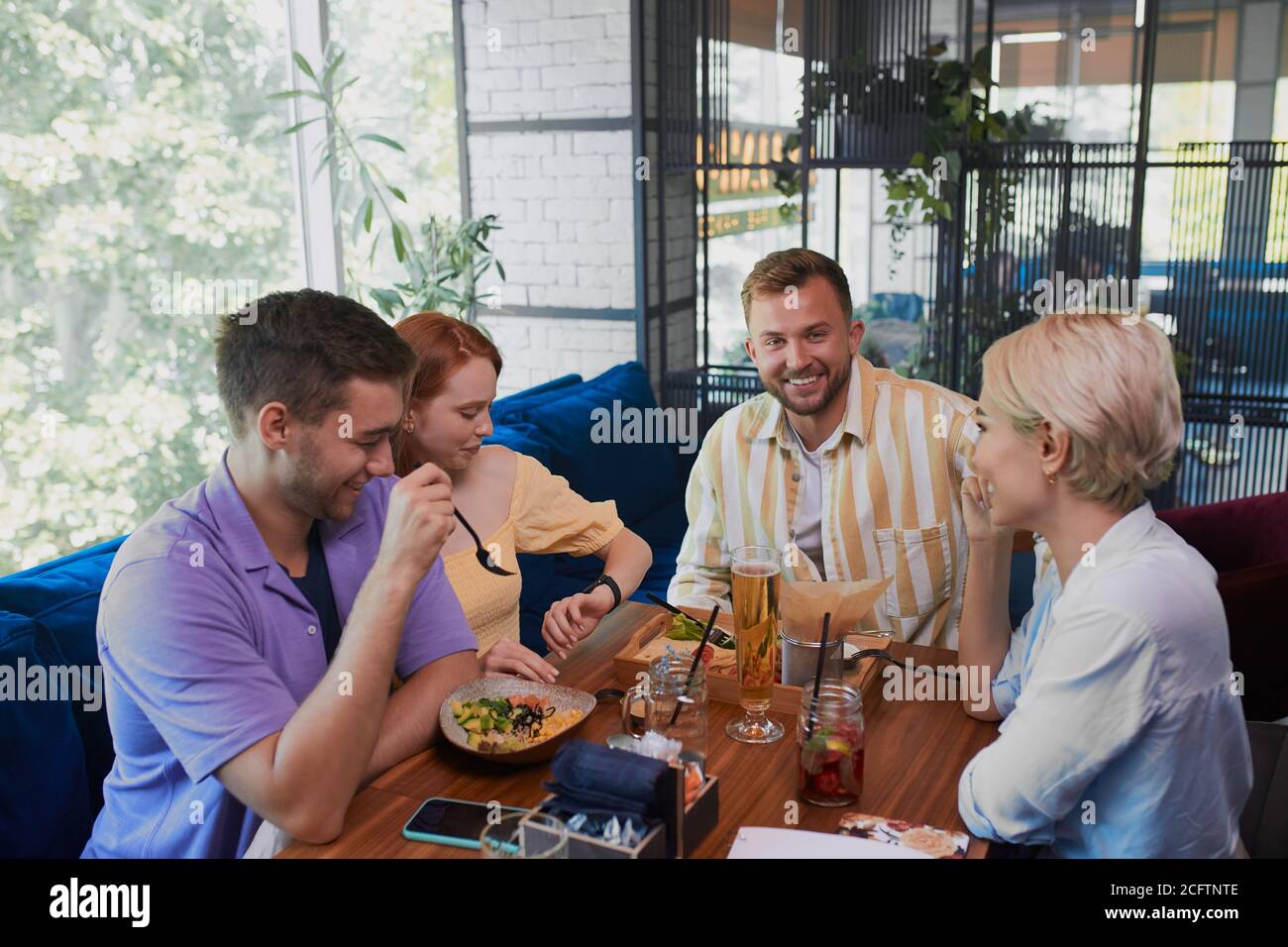 felici amici caucasici non si incontrarono a lungo, si riunivano in ristorante o bar, si mangiavano, discutevano notizie Foto Stock