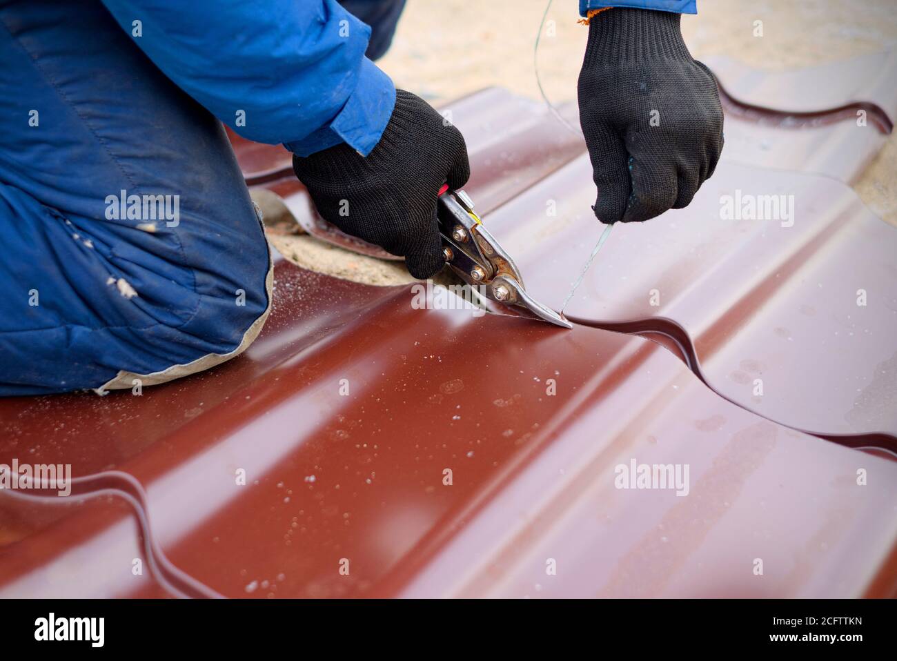 Il lavoratore usa le forbici per tagliare la lamiera di copertura metallica  Foto stock - Alamy