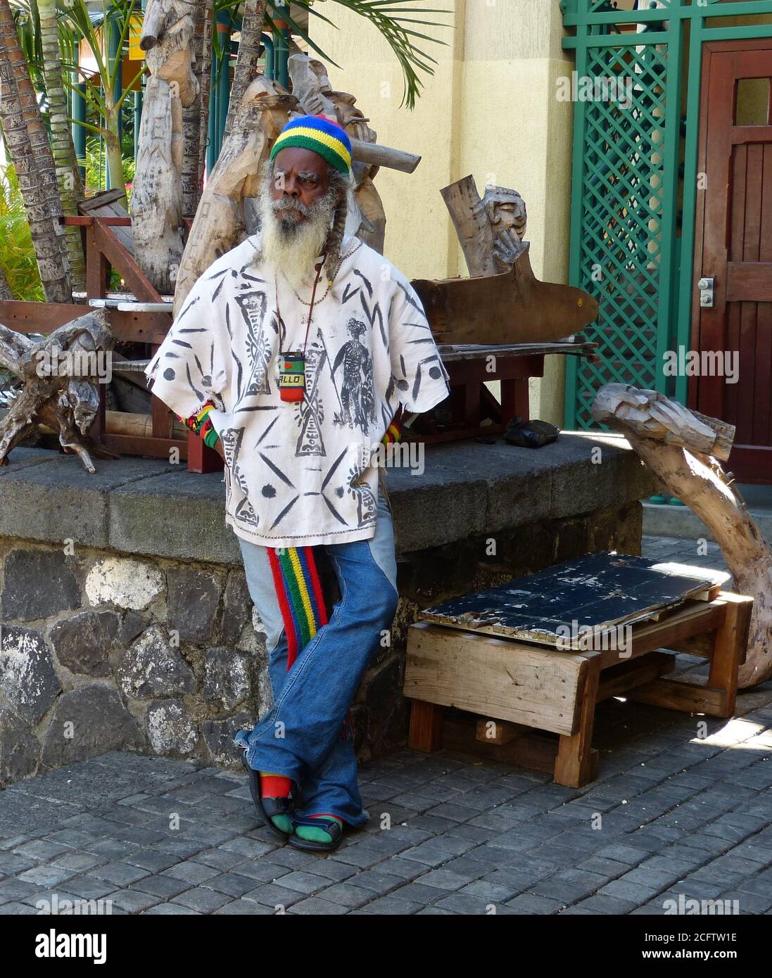 L'uomo anziano hippie e rastaman sulla strada ascolta la musica. Antico eccentrico Mauriziano in abiti luminosi. Gente dell'isola di Mauritius. Foto Stock