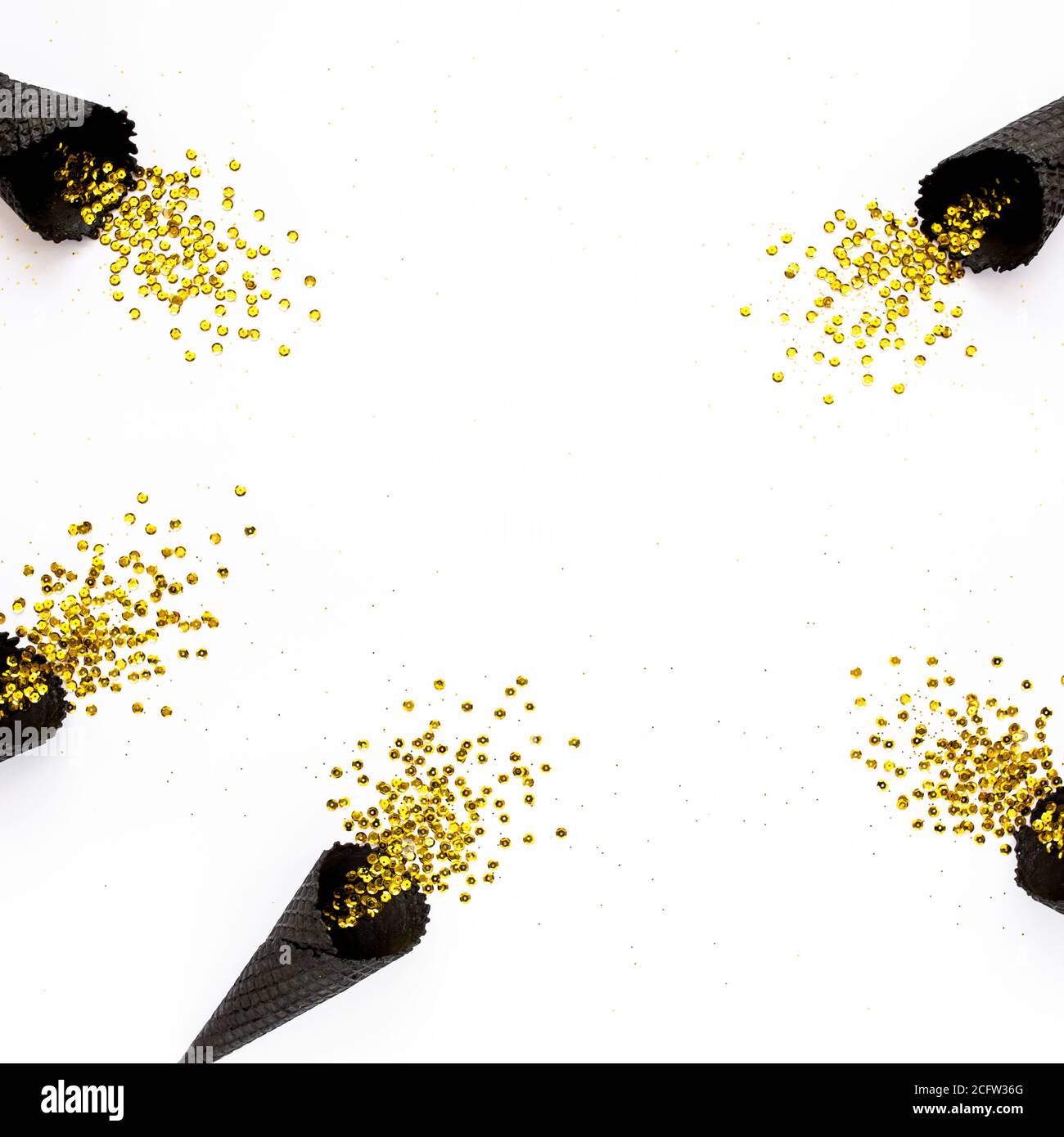 Coni di cialda neri con spoletta di confetti dorati isolati su sfondo bianco. Disposizione piatta, vista dall'alto, concetto di festa minimo. Foto Stock