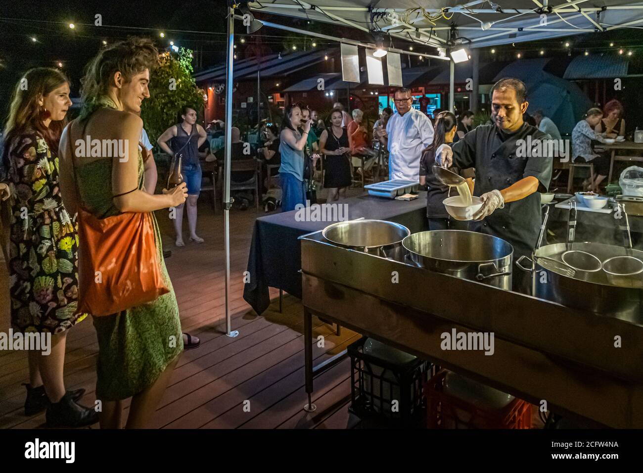 Uno chef versa's miso e brodo di soia per gli ospiti a uno stand di zuppe, con Jimmy Shu del ristorante Hanuman visibile in lontananza al mercato del Deckchair Cinema a Darwin, Territorio del Nord, Australia. Foto Stock