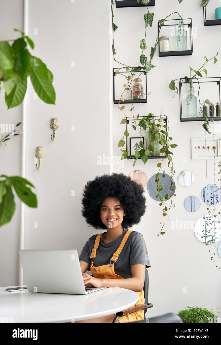 Felice studente di signora africana che usa il computer portatile siediti al tavolo in un caffè guardando la macchina fotografica. Foto Stock
