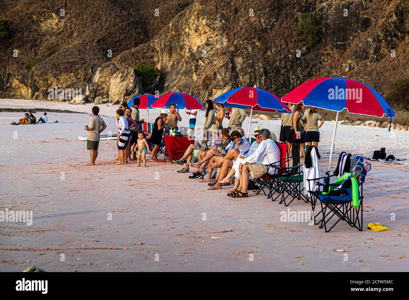Picnic sulla spiaggia rosa di Pulau Padar. Le bevande in spiaggia sono accompagnate da tartine di formaggio di capra Meredith con cipolle caramellate. Crociera con fuoco e draghi del vero Nord, Isole Sunda, Indonesia Foto Stock