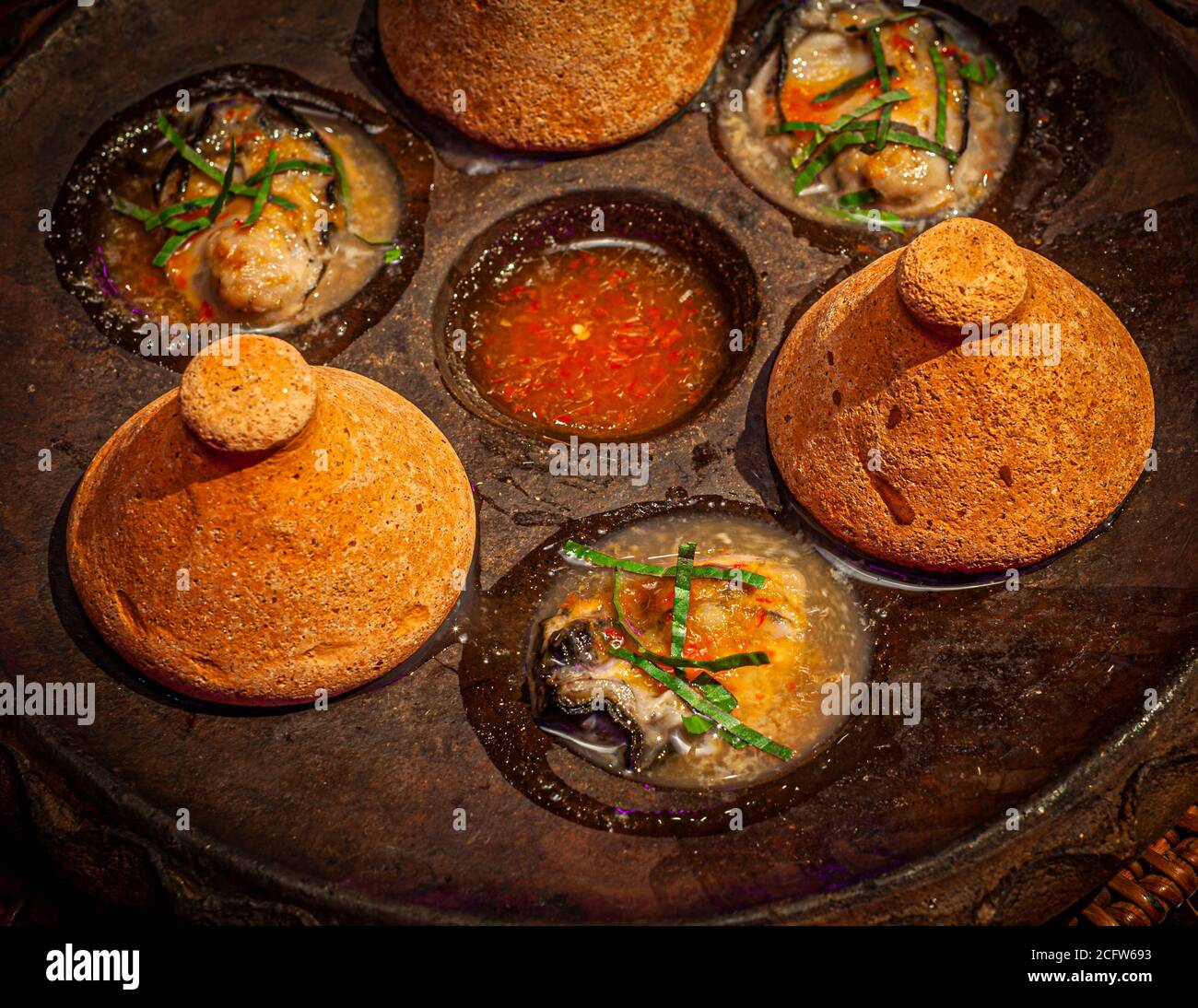 Ricoperti di coperchi conici in ceramica, i caldi ostriche Hanuman arrivano sul tavolo. Cucina-Chef Jimmy Shu di Hanuman a Darwin, territorio del Nord, Australia Foto Stock