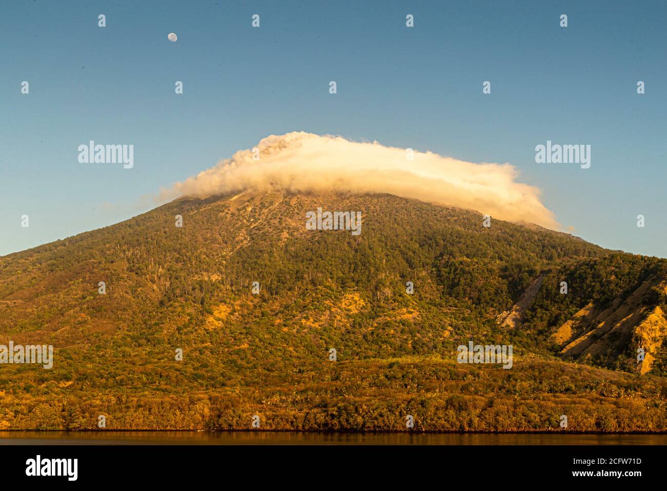 Isola vulcanica indonesiana dietro un sipario di nuvole, Isole Sunda, Indonesia Foto Stock