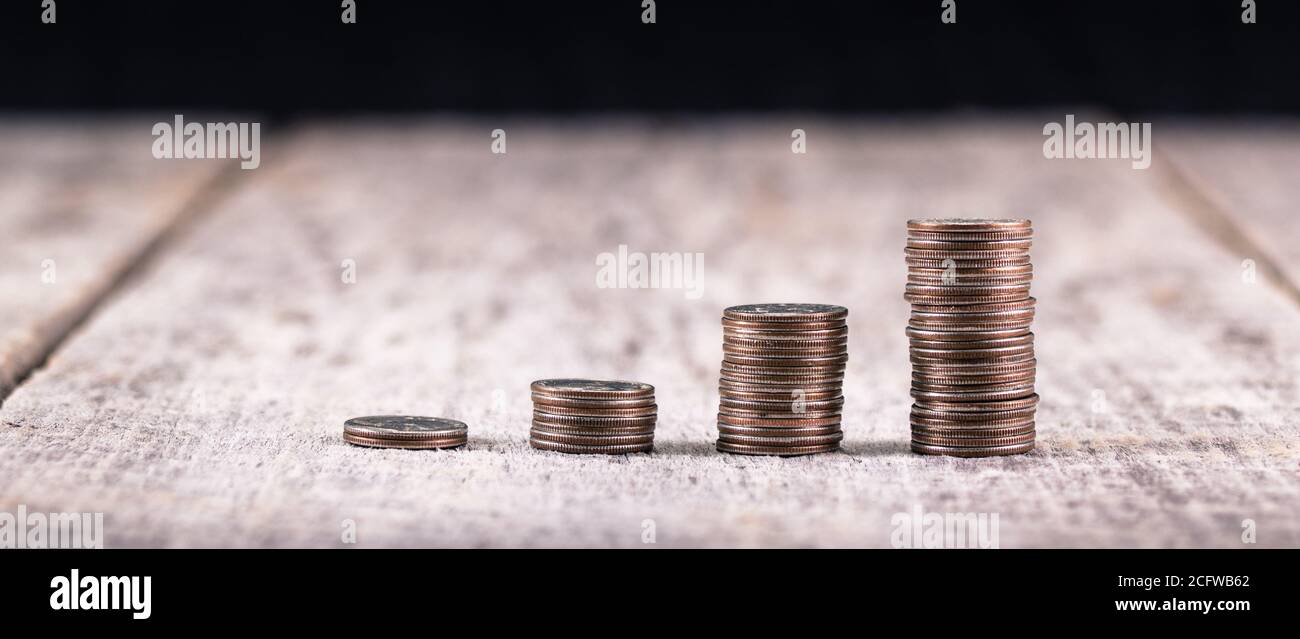 Pile di quarti su un vecchio tavolo di legno / investimento concetto di crescita Foto Stock
