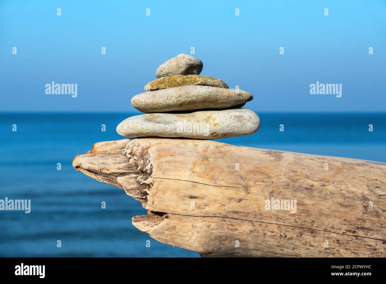 Pila di pietre di ciottoli su un ceppo. Spiaggia di Toila, Estonia Foto Stock