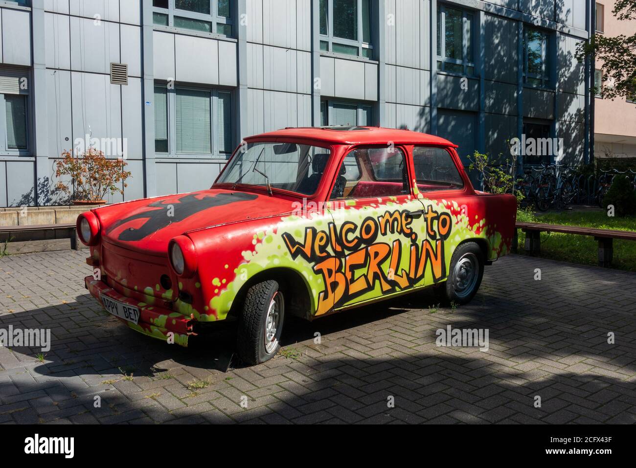 Graffiti "Benvenuti a Berlino" dipinti sulla vecchia auto Trabi della Germania orientale fuori dall'hotel, Berlino Foto Stock