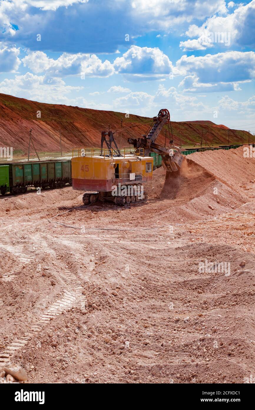 Estrazione e trasporto di minerali di alluminio. Estrazione aperta di argilla bauxite. Carico di minerale con escavatore elettrico in carri ferroviari. Foto Stock