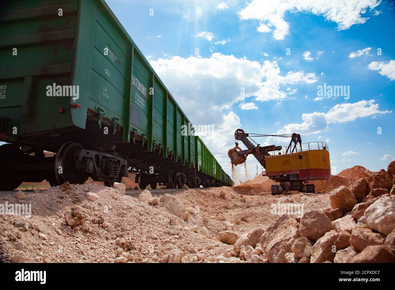 Estrazione e trasporto di minerali di alluminio. Argilla bauxite aperta taglio miniera. Escavatore elettrico che carica il minerale nel treno tramogge. Foto Stock