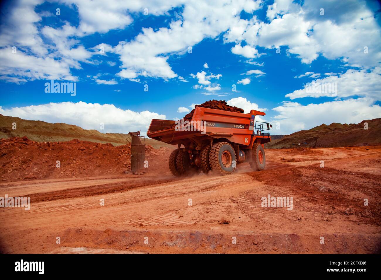 Miniera a taglio aperto. Estrazione e trasporto di minerali di alluminio. Estrazione in cava. Un autocarro da cava arancione Hitachi con argilla bauxite. Foto Stock
