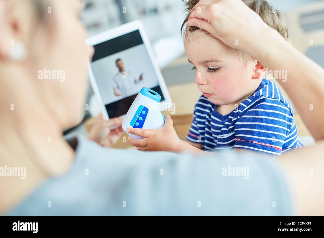 Madre e bambino malato che misura una febbre in linea consultazione nella videochat Foto Stock