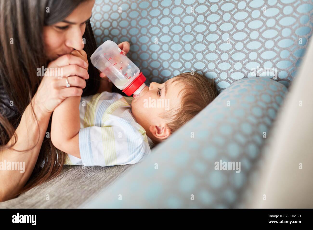 La madre dà il biberon di latte sul divano come concetto per amore e cura Foto Stock