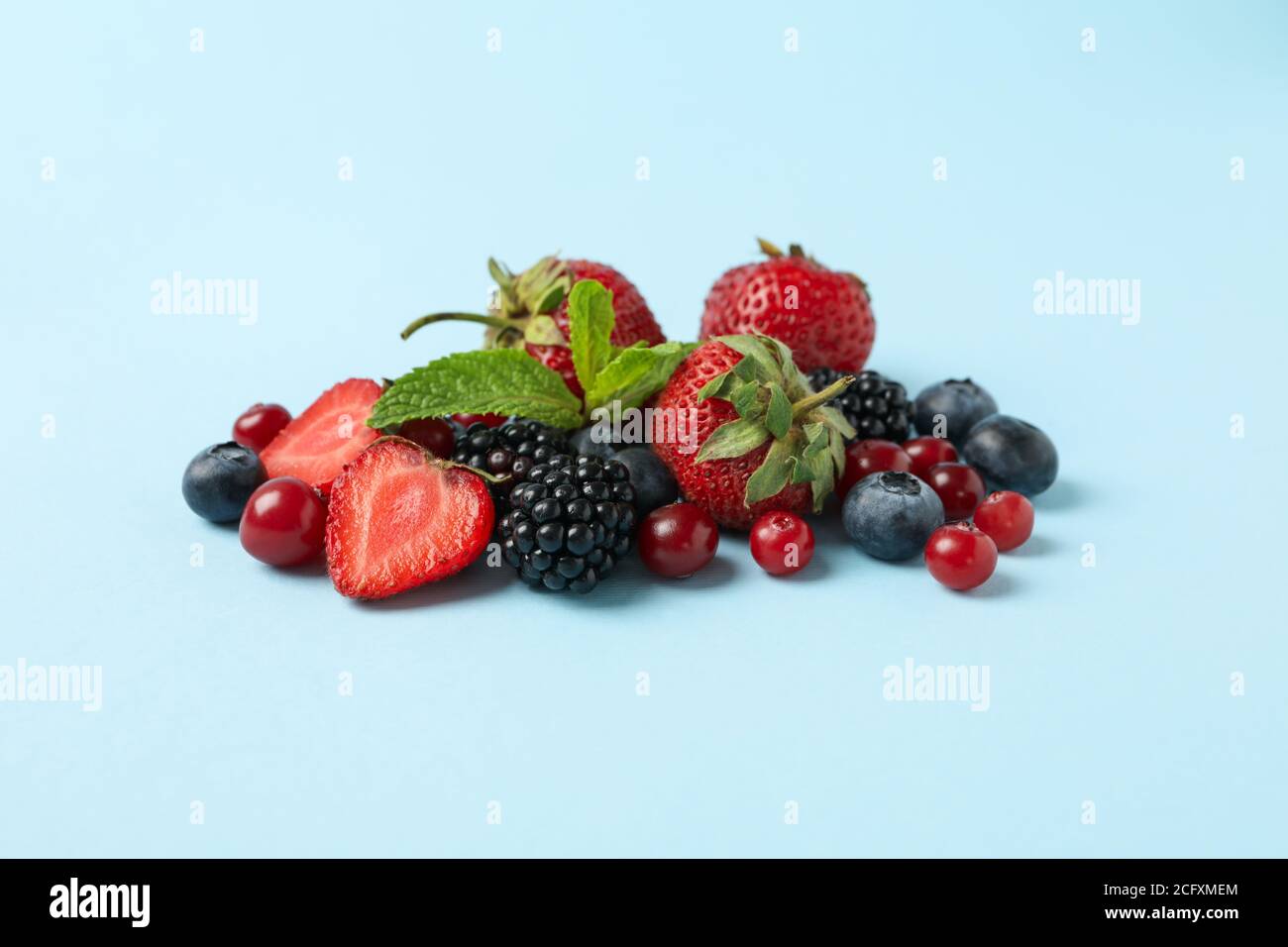 Mescolare le bacche fresche su sfondo blu, spazio per il testo Foto Stock