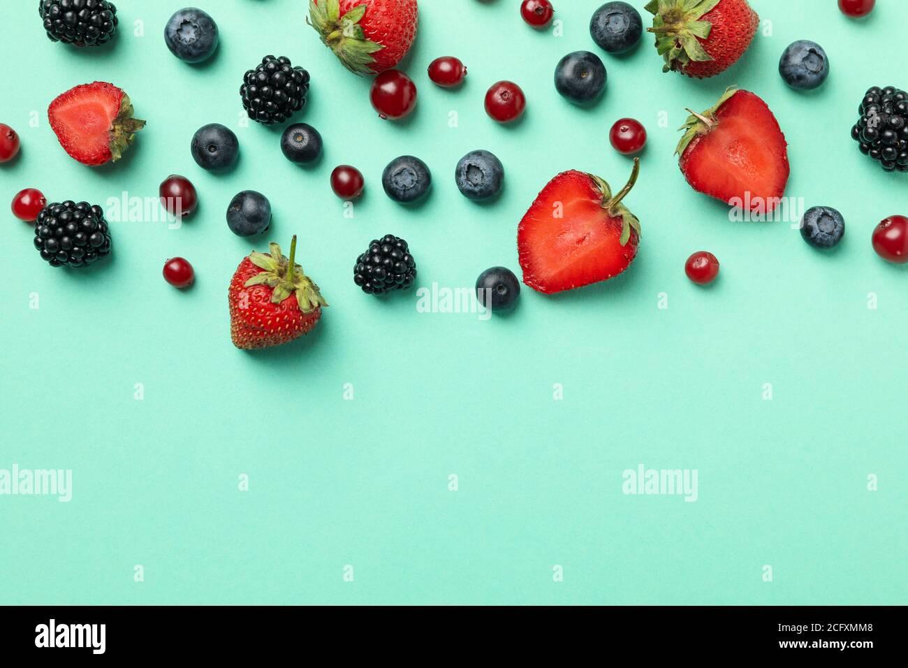 Mix di bacche fresche su sfondo menta, vista dall'alto e spazio per il testo Foto Stock