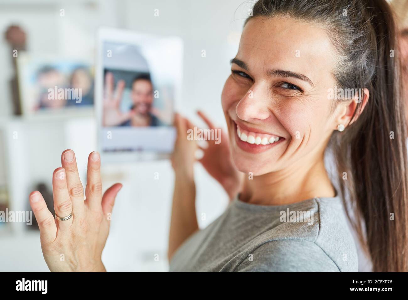 Felice giovane donna che usa il tablet durante la chat video online con il suo partner Foto Stock