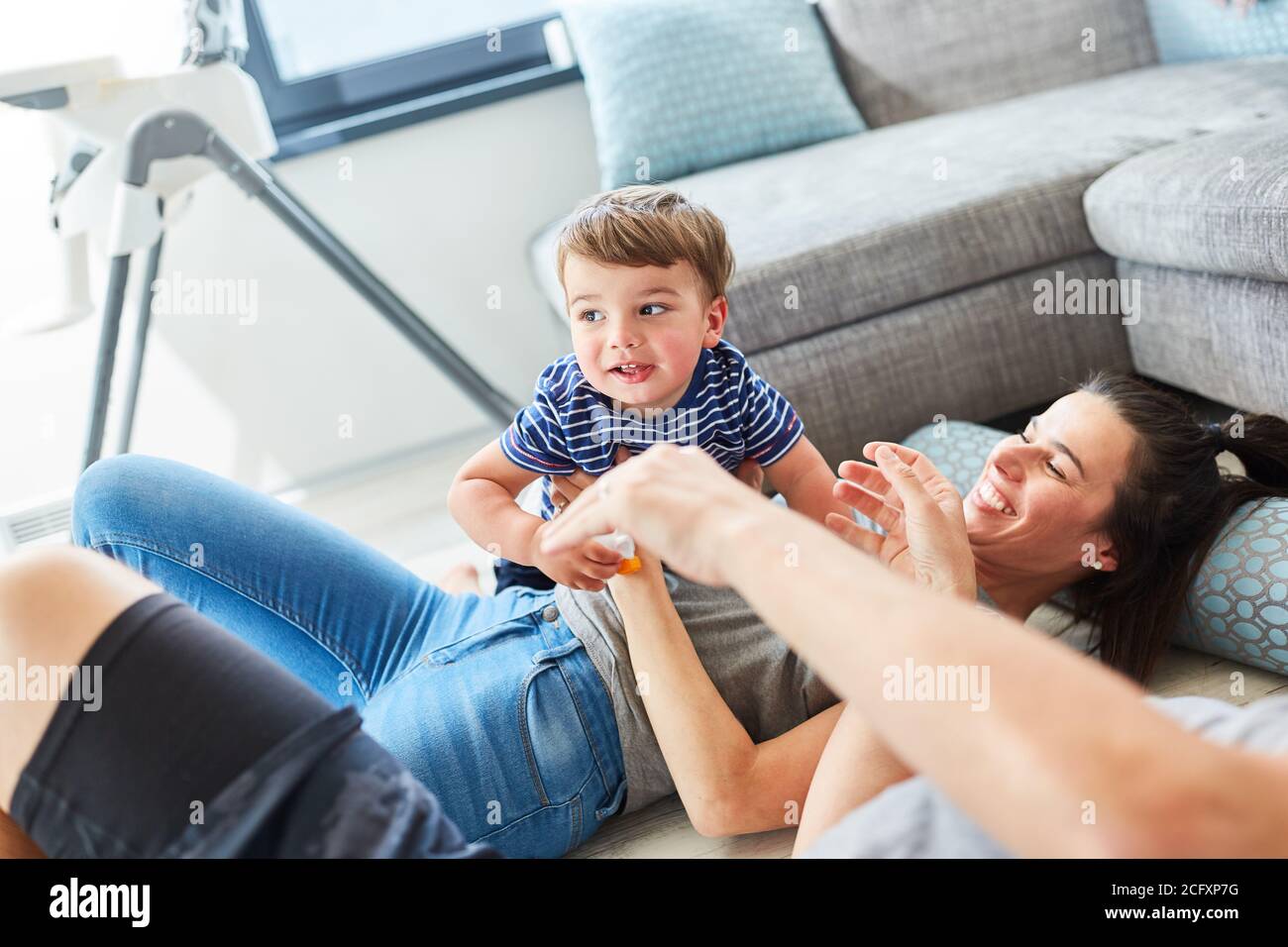 Madre e bambino coccolano e giocano insieme sul pavimento nel soggiorno Foto Stock