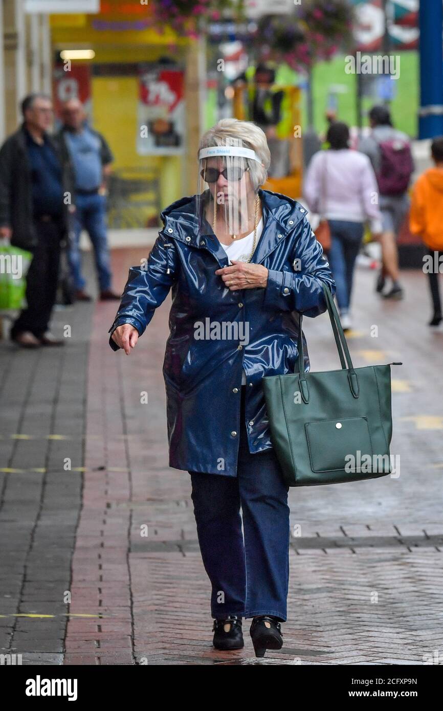 Gli acquirenti indossano i DPI nel centro di Caerphilly, poiché il distretto della contea nel Galles meridionale deve essere posto sotto un blocco locale a seguito di un "aumento significativo" nei casi di coronavirus. Il governo gallese ha detto che non sarà consentito entrare o uscire dall'area senza una ragionevole scusa quando le restrizioni entreranno in vigore martedì alle 18:00. Foto Stock