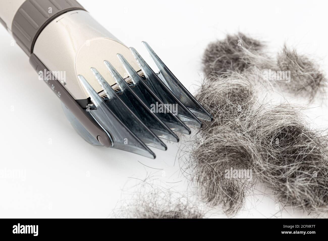 Primo piano del regolacapelli e taglio dei capelli isolati su sfondo bianco. Strumento per tagliare i capelli Foto Stock