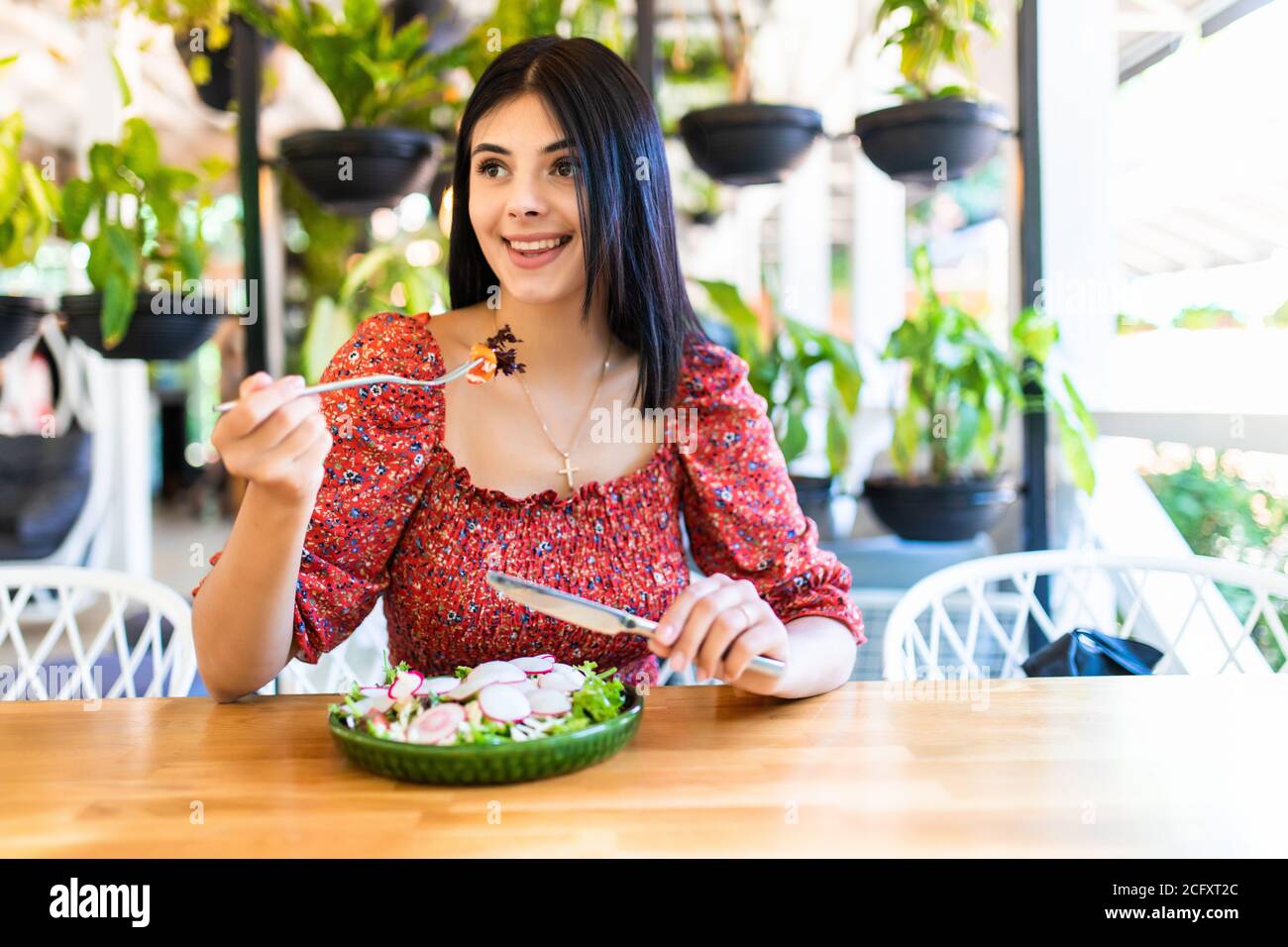 Donna sorridente mangiare insalata fresca nel ristorante Foto Stock