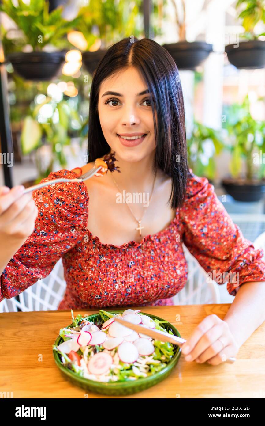 Donna sorridente mangiare insalata fresca nel ristorante Foto Stock