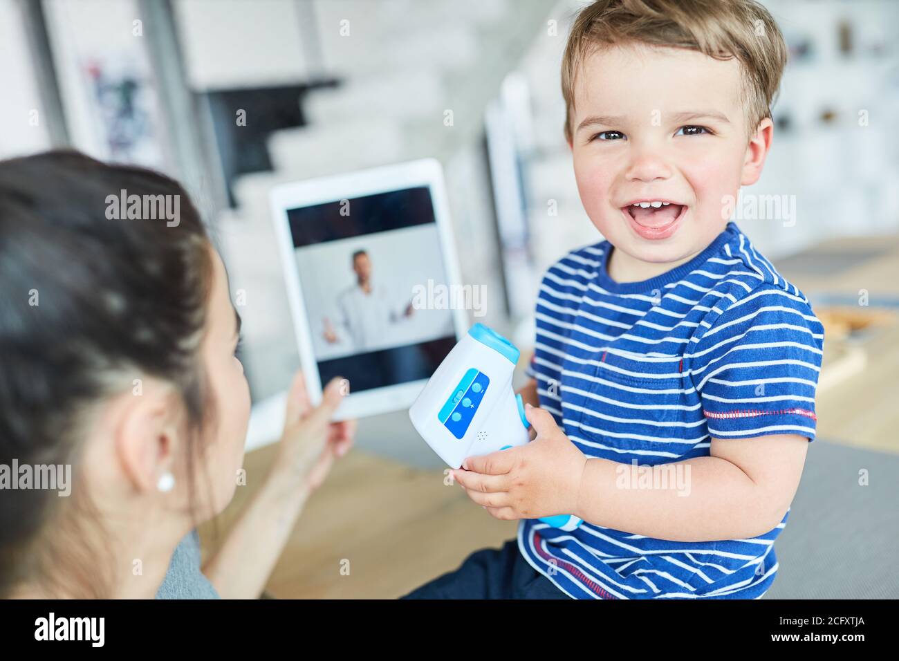 Ridendo bambino con termometro clinico nella consultazione online con pediatra Foto Stock